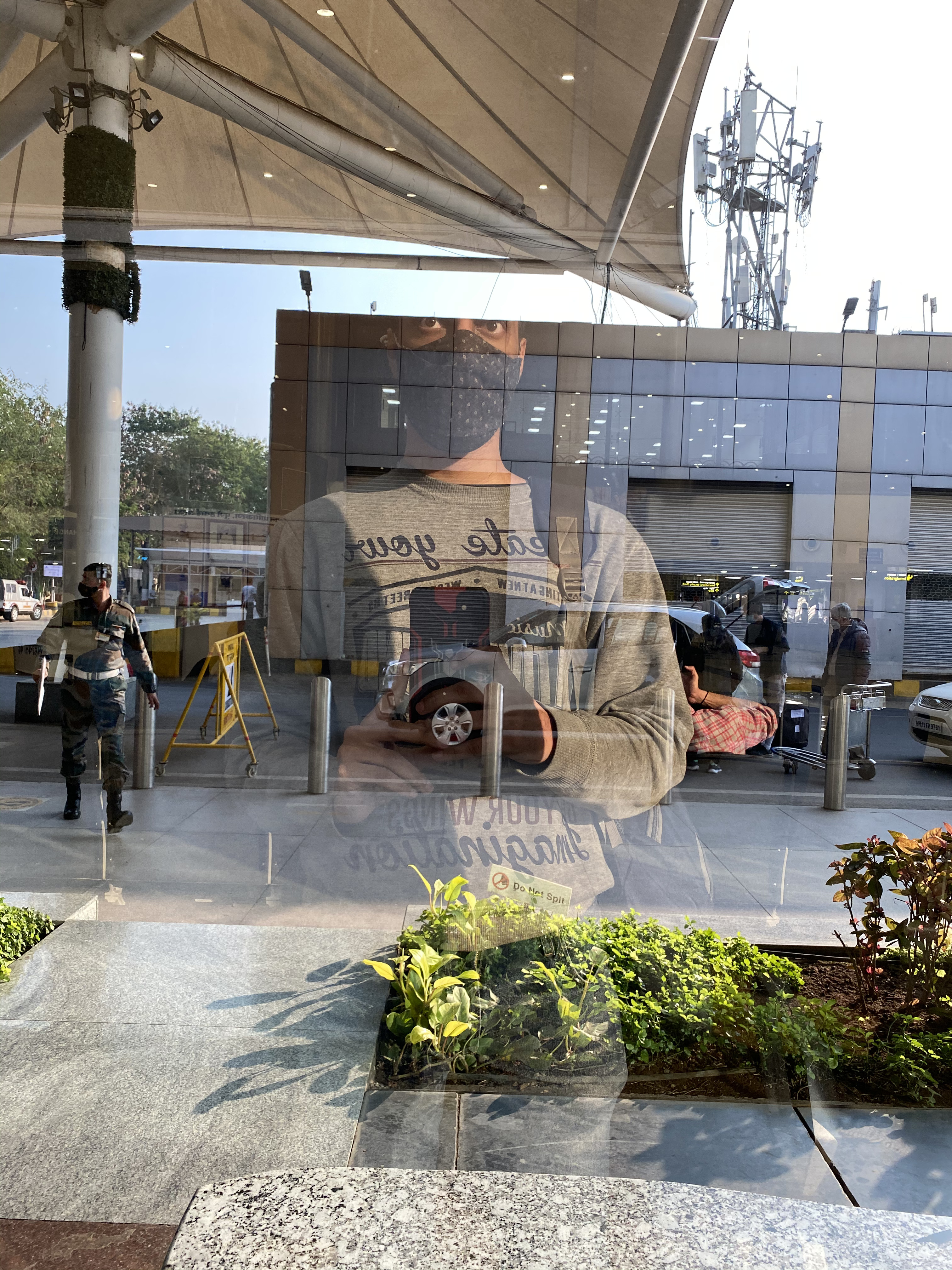 Masked self-portrait reflected in an airport terminal window